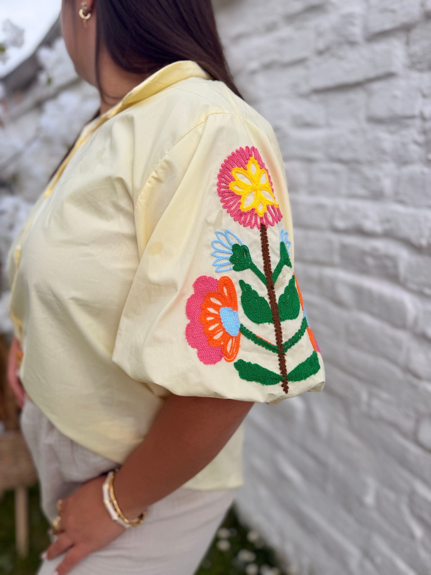 Chemise jaune pâle aux manches ballon et motifs fleuris.